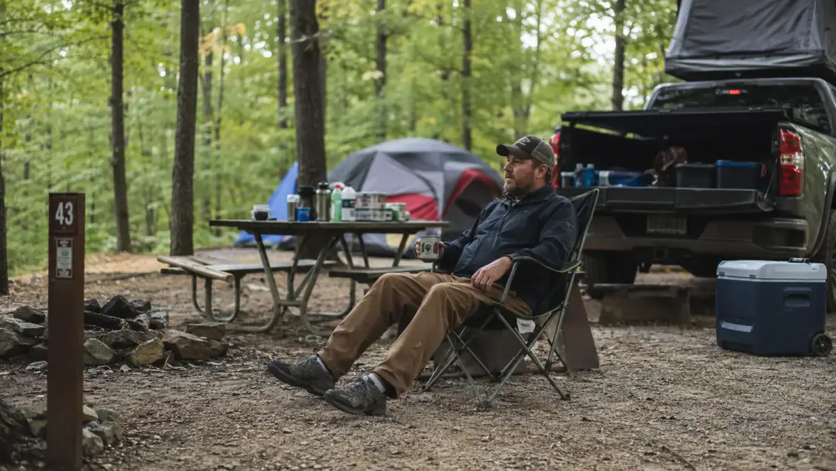 Wide shot of a camping chair leg stance test on soft dirt ground at a campsite