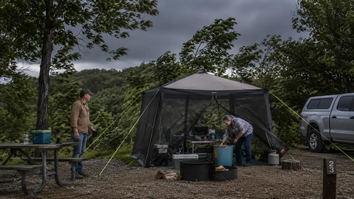 Screen house canopy holding steady at a campsite during windy, overcast weather